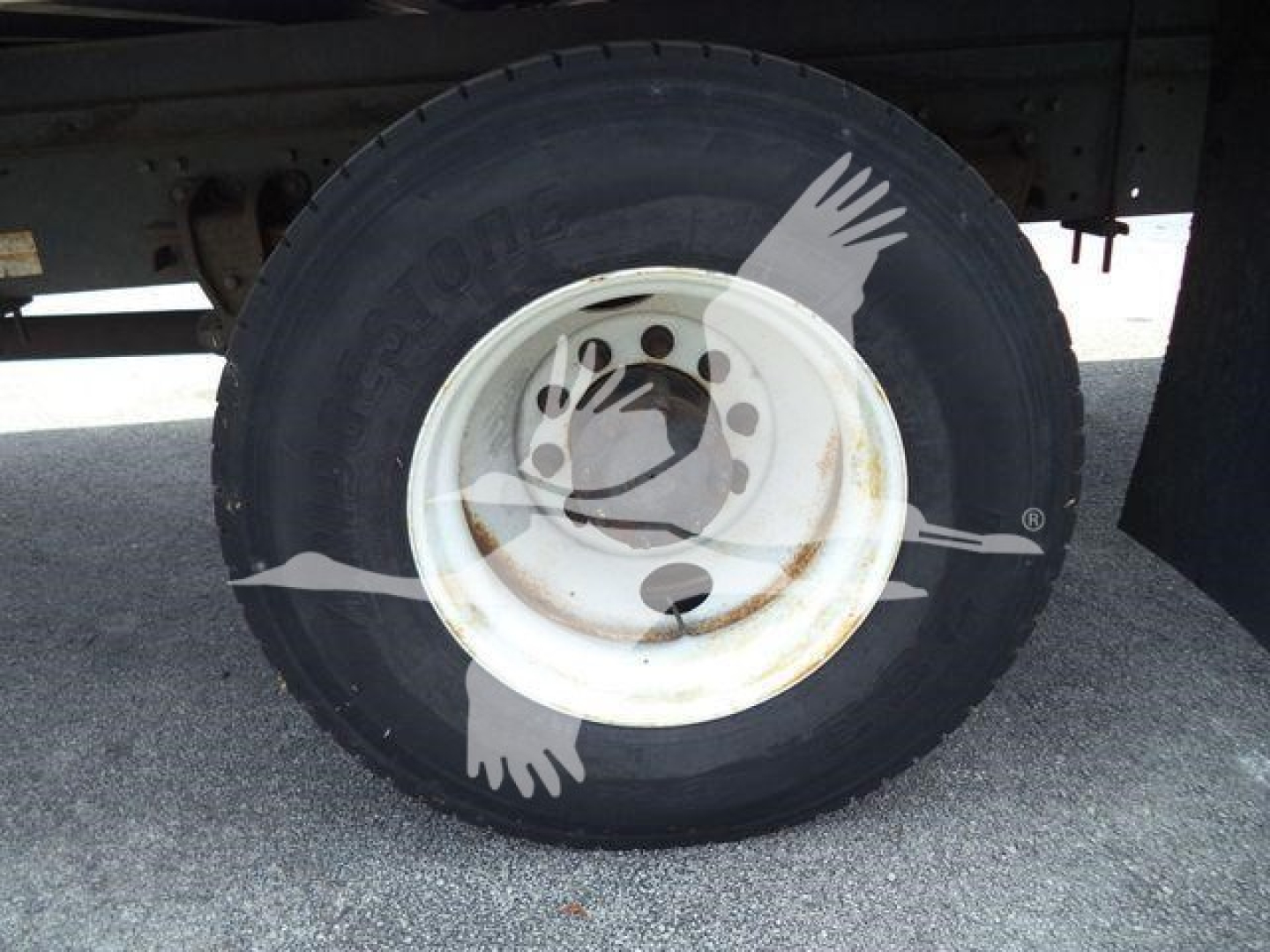 Wheel and tire on a refrigerated truck showing steel white wheel and dark tire with faint logo overlay.
