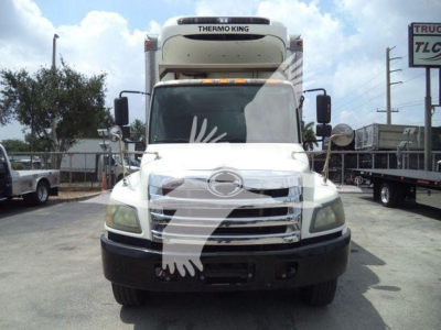 Front view of a white refrigerated 2015 Hino 268A truck with Thermo King unit on the cab top, large grille, and black bumper. Windshield wipers visible.