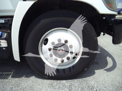 Truck wheel and fender of a 2015 Hino 268A refrigerated truck showing front wheel and part of the body.