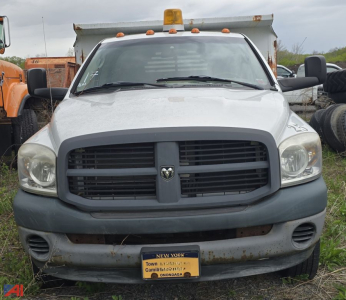 Dodge Ram 3500 heavy duty dump truck front view showing grille, headlights, and yellow warning beacon; New York license plate on bumper.