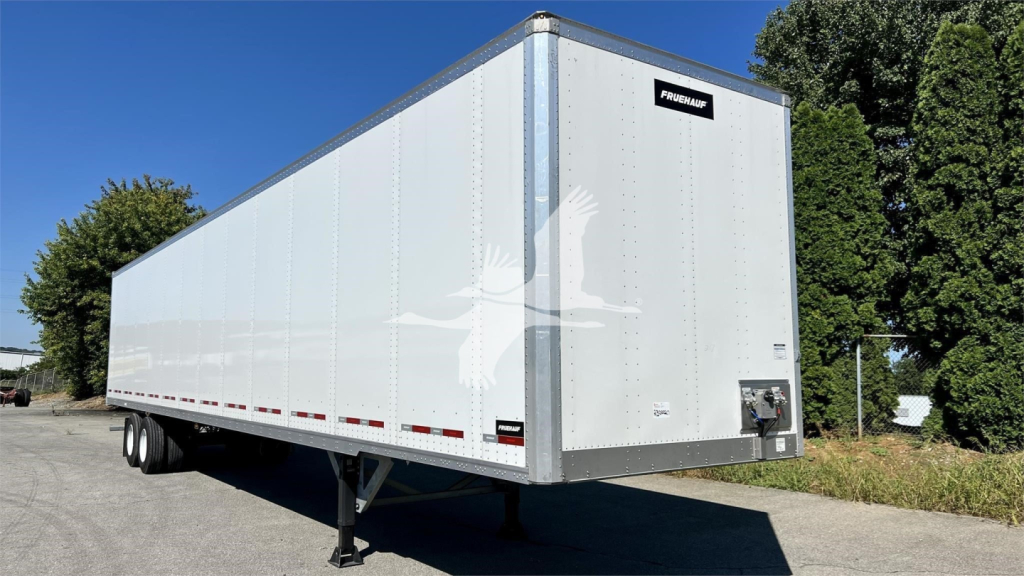Fruehauf trailer van showing side view with front access and rear bumper, white aluminum exterior.