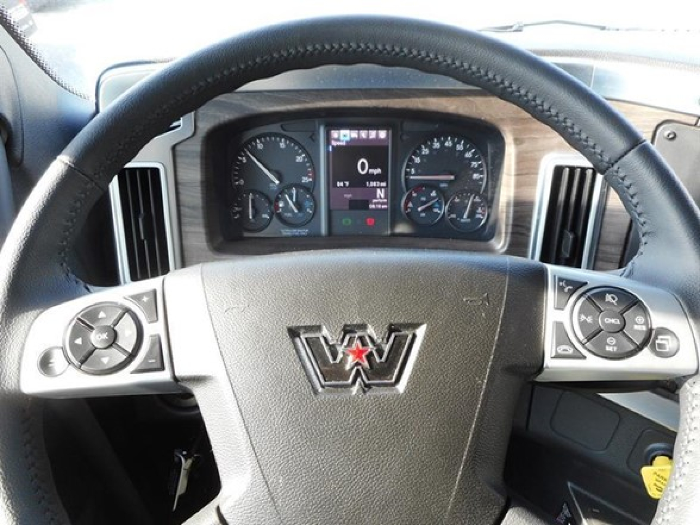 Truck cabin steering wheel and instrument cluster with Western Star logo on the steering wheel; dashboard controls visible.
