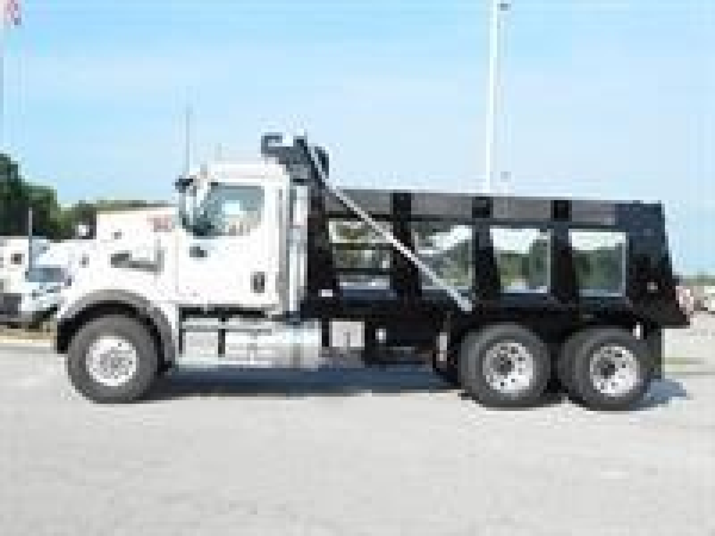 Western Star 47X dump truck in side profile with white cab and black dump bed.