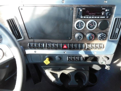 Dashboard of a Western Star truck showing radio, gauges, switches, ignition, and cup holders.