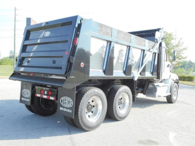 Dump truck side/rear view showing bed, multiple axles, and rear tires with Western Star branding and stock number decals.
