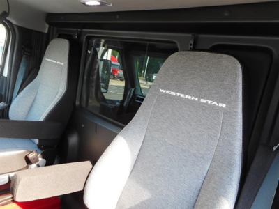 Interior of a brand-new Western Star 47X dump truck showing gray upholstered seats with Western Star logos and side window view.