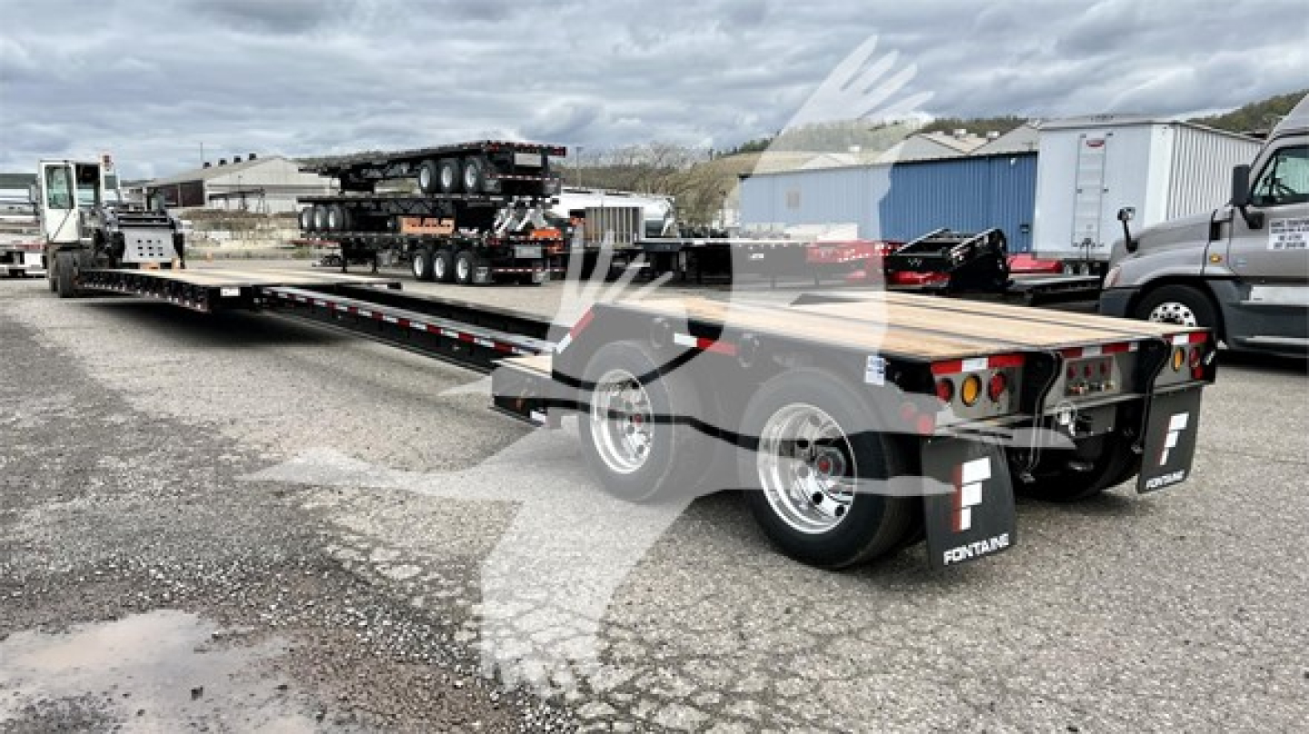 Lowboy trailer showing flatbed with dual rear axles and tandem wheels, Fontaine branding on mudflaps, steel deck, loading ramps at rear, and utility equipment on trailer