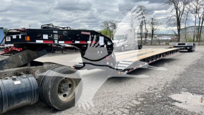 Lowboy trailer showing Fontaine Renegade XN20 with long flatbed on a trailer yard.
