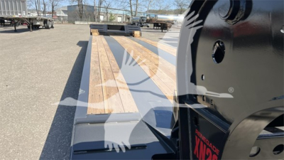 Lowboy trailer bed with wooden deck extending toward the hitch; Fontaine Renegade XN20 branding on the tractor tongue; clear view of flatbed rails and pin hole.