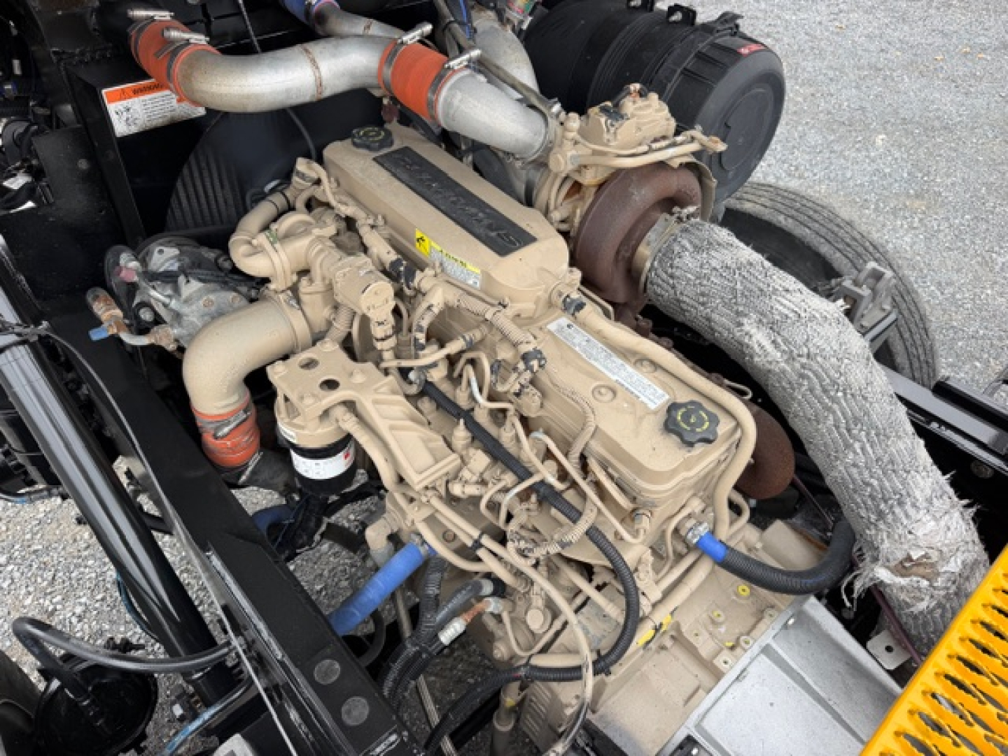 Yard truck engine bay showing TJ5000 capacity engine with beige hoses and turbo, various labels, and exposed components.