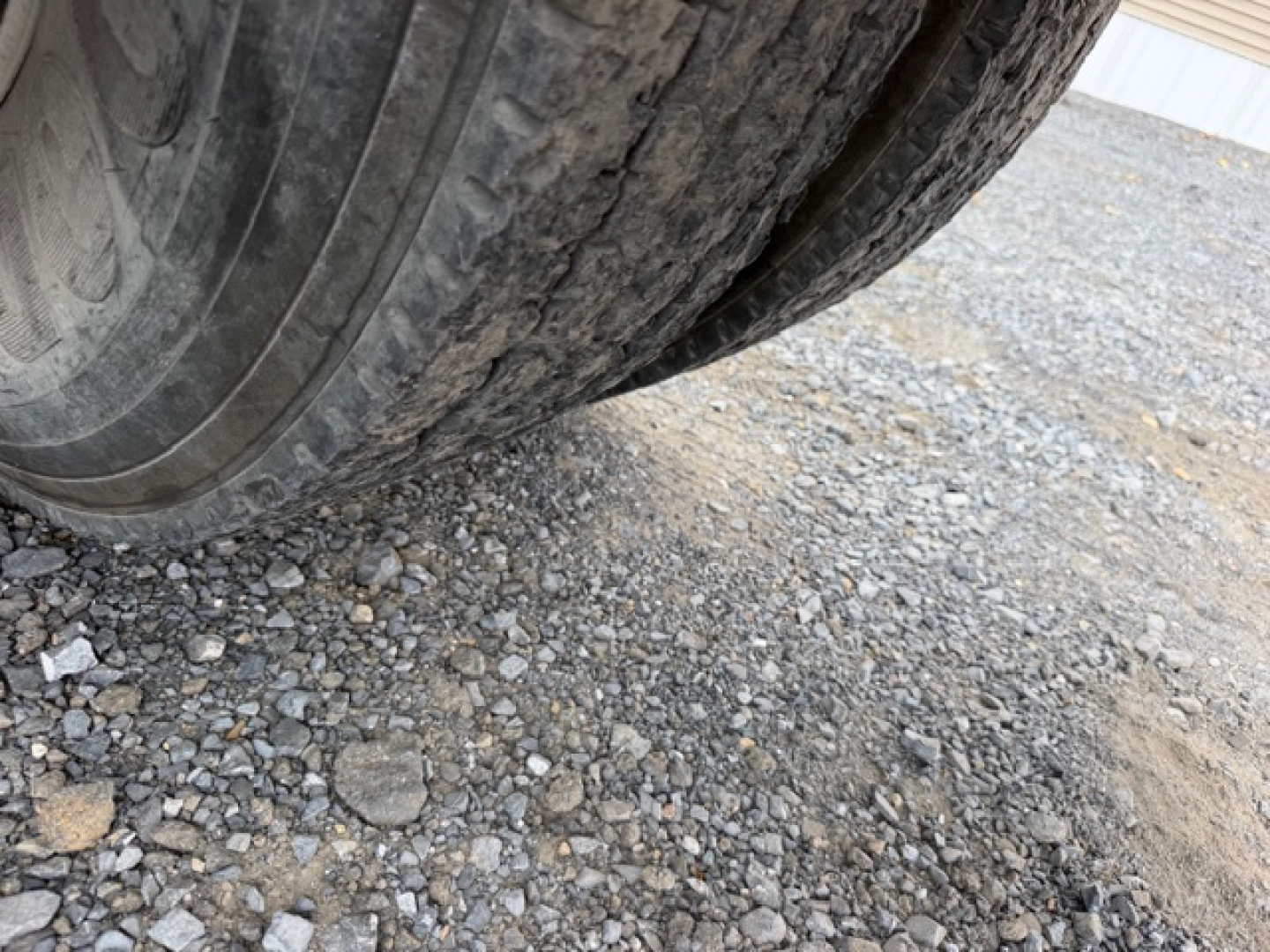 Tire close-up on a heavy truck with gravel ground visible underneath.