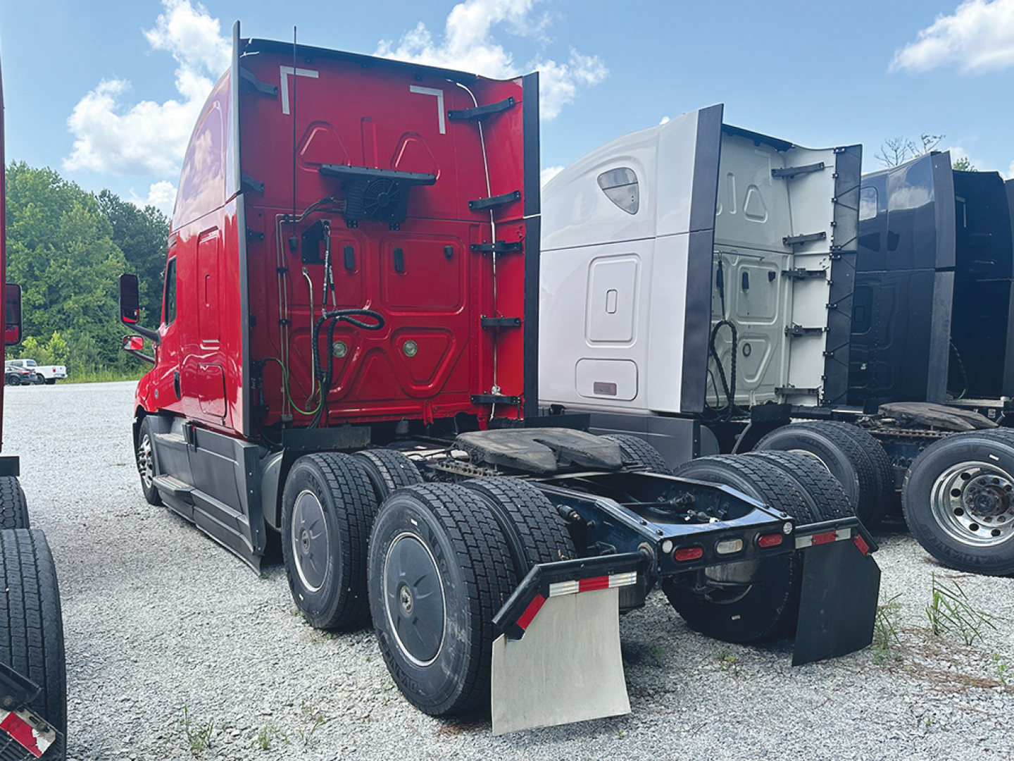 Freightliner Cascadia126 conventional sleeper truck rear-left view showing red cab and chassis with dual rear axles and fifth wheel.