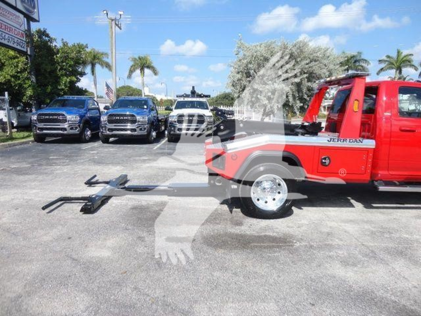 Truck at dealership with red Ram 4500 SLT winch setup on flatbed frame. Several Ram pickups in background.