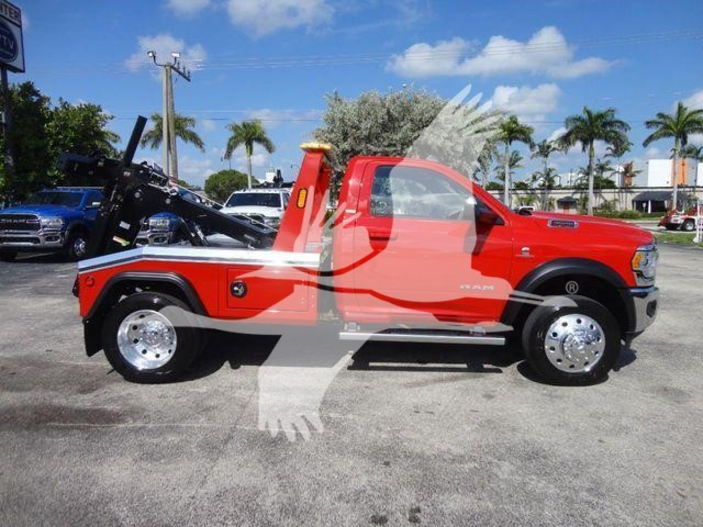 Red Ram 4500 pickup truck with winch and utility bed, side profile view, blue sky palm trees in background