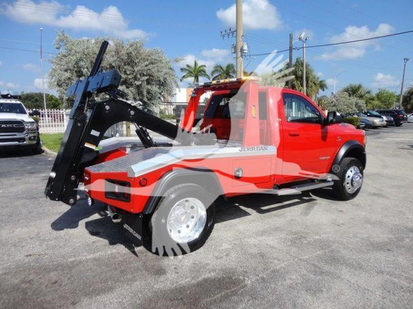 Ram 4500 Tow Truck with hydraulic lift and winch in red and gray livery, side view showing front wheel, truck cab, and winch apparatus.