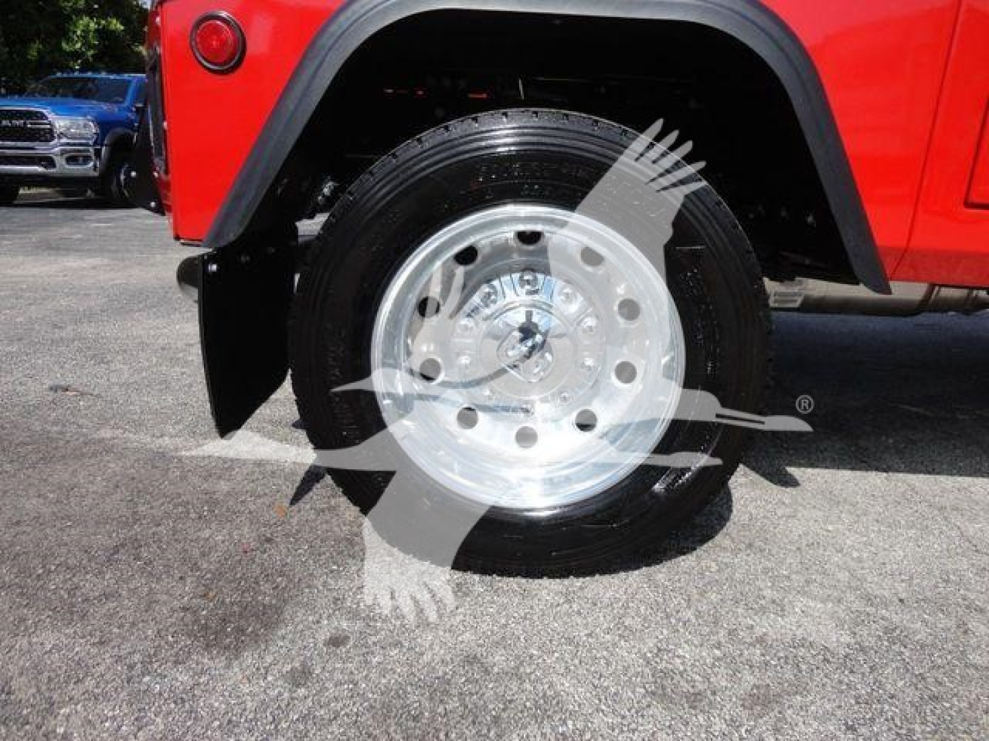 Truck wheel well and front tire of a red Ram 4500 with a polished alloy wheel and black fender flare. visible text on wheel includes small center cap markings.