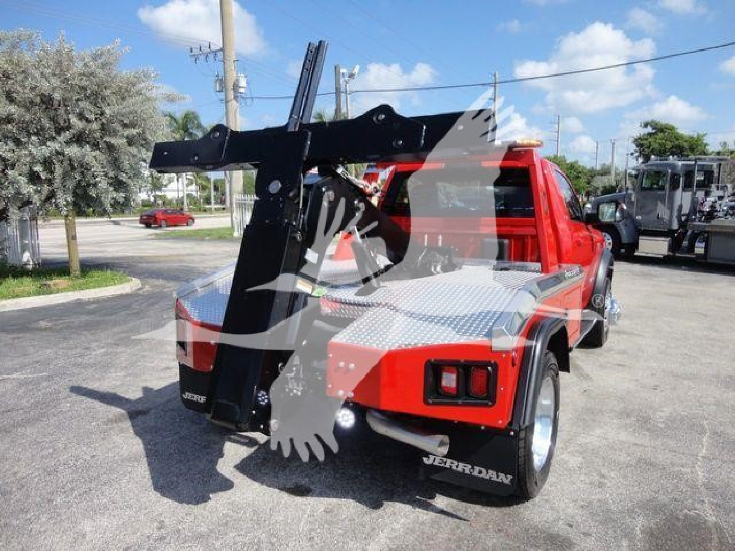 Ram 4500 SRW rear view with integrated winch and hydraulic arm, red body, black equipment rack, white logo on fender, truck bed with diamond plate surface.