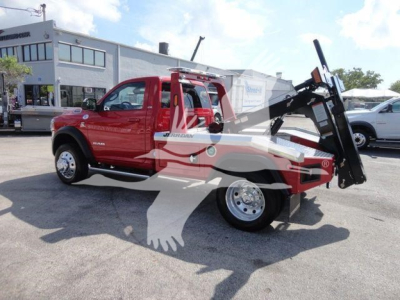 Ram 4500 tow/haul truck with red cab and raised front winch assembly, side view showing tilt bed and large hydraulic winch arm.