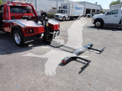 Ram 4500 pickup tow truck with a mounted winch system and trailer hitch on a sunny day; red tow truck body, metal winch mount, and extended metal tow bar in foreground.