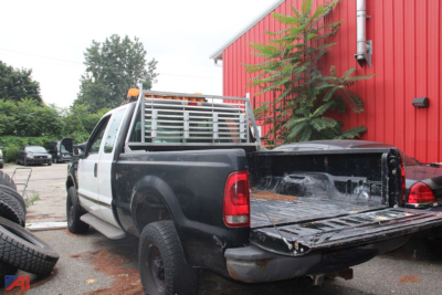 2004 Ford F-250 Super Duty pickup truck rear/side view showing flatbed and dual rear wheels, extended cab, in an outdoor lot.