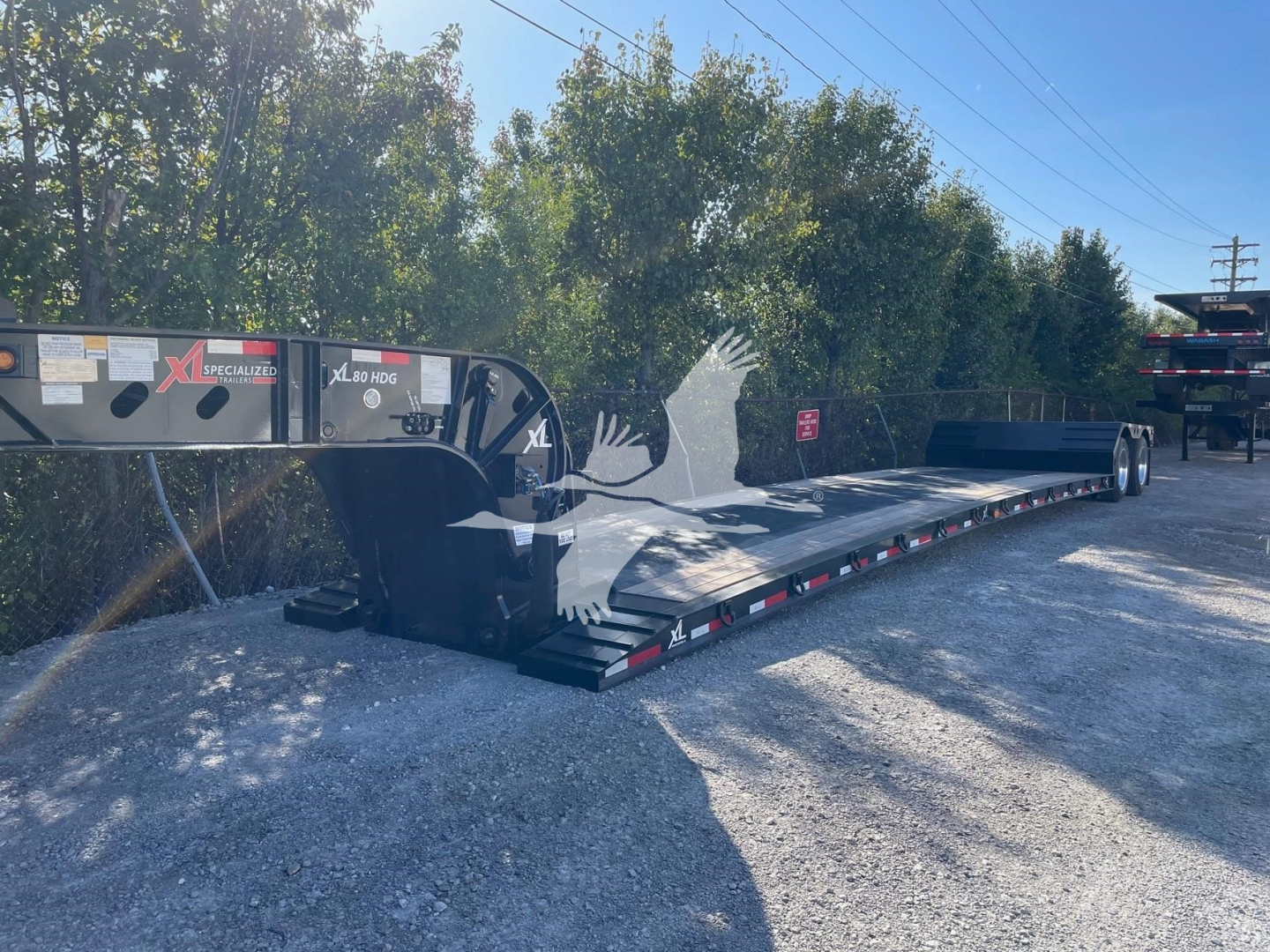 XL Specialized Mini Deck double drop expandable trailer showing long flat deck with hydraulic gooseneck and side decals.