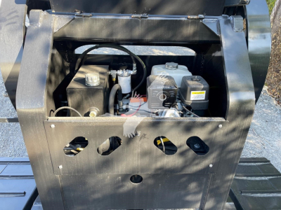 Mini deck trailer engine bay showing engine components and hydraulic reservoir with label unreadable.