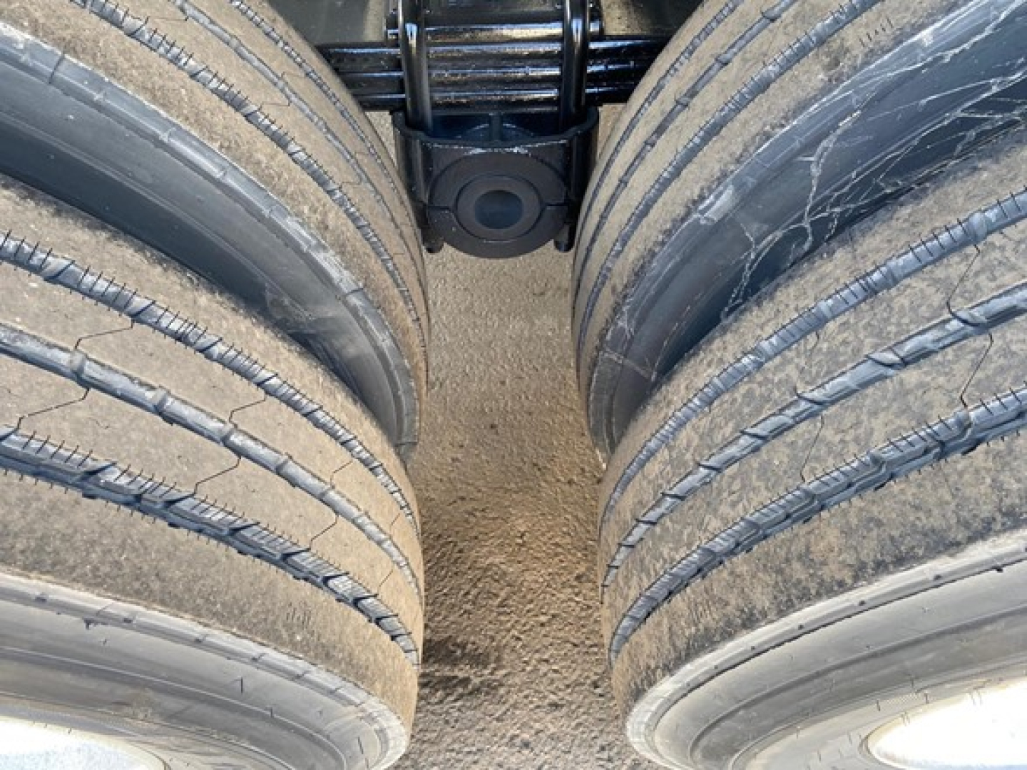 Trailer axle and dual tires view showing suspension and hub area between two wheels on a new dump trailer
