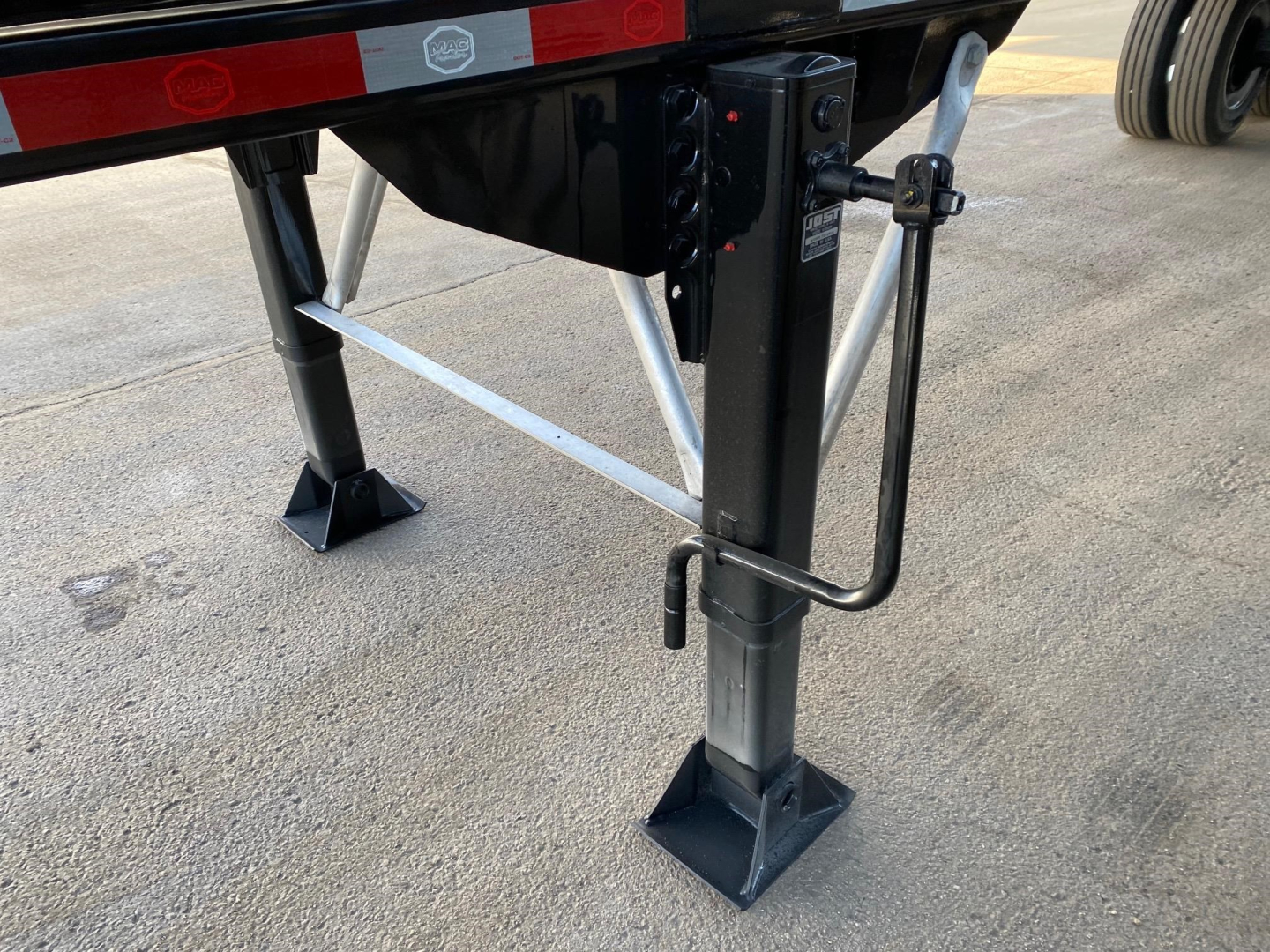Dump trailer landing gear with legs and support braces visible under a black trailer frame.