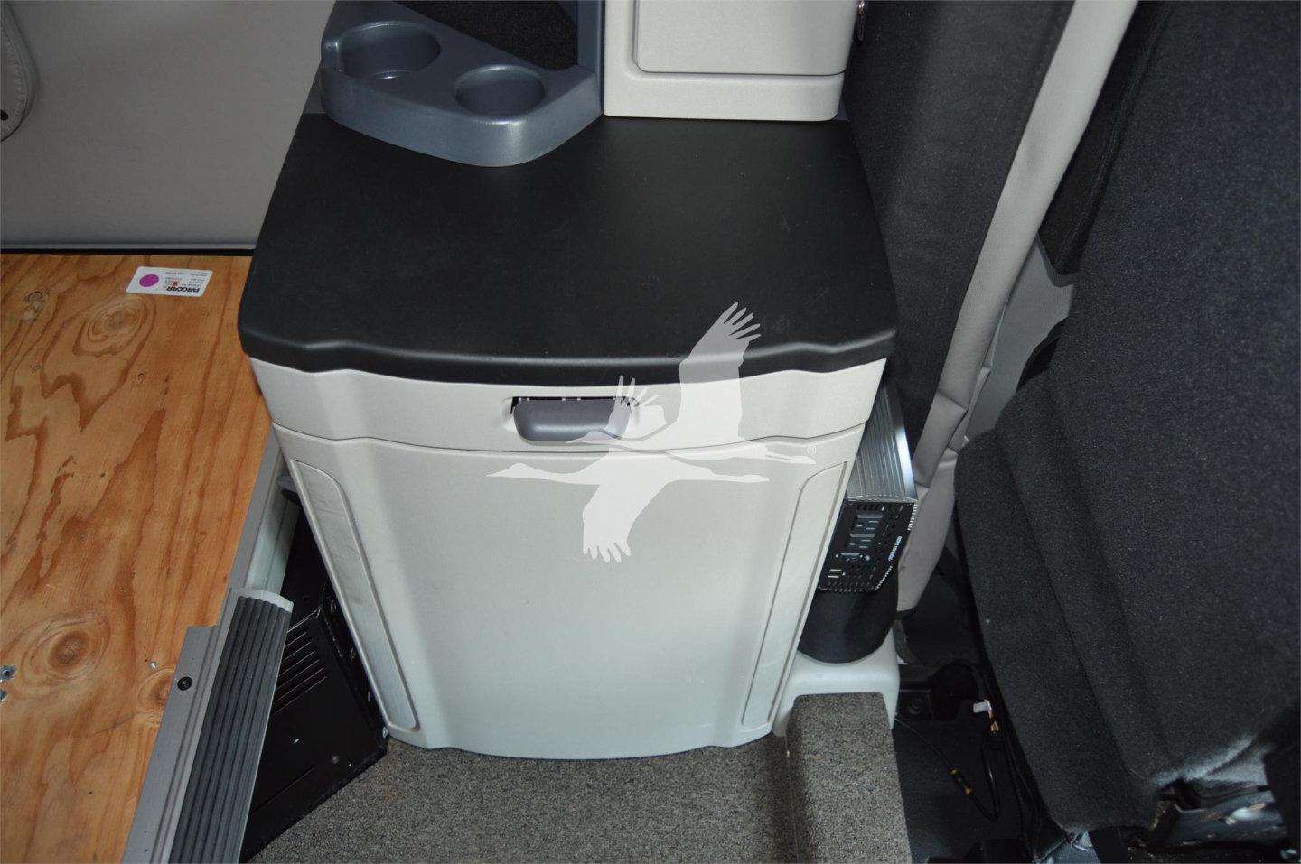 In-vehicle area showing a white/gray cabinet with a black top inside a Peterbilt 579 sleeper cab. Visible text includes a small label and control panel near the cabinet.