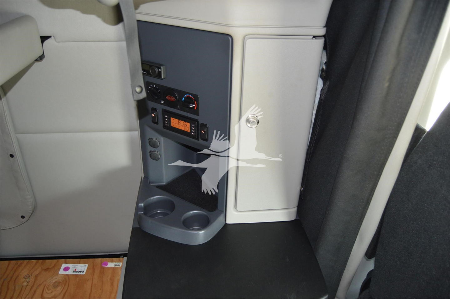 Peterbilt 579 cab interior showing control panel and storage area near passenger seat, 12V power outlet and cup holder visible.