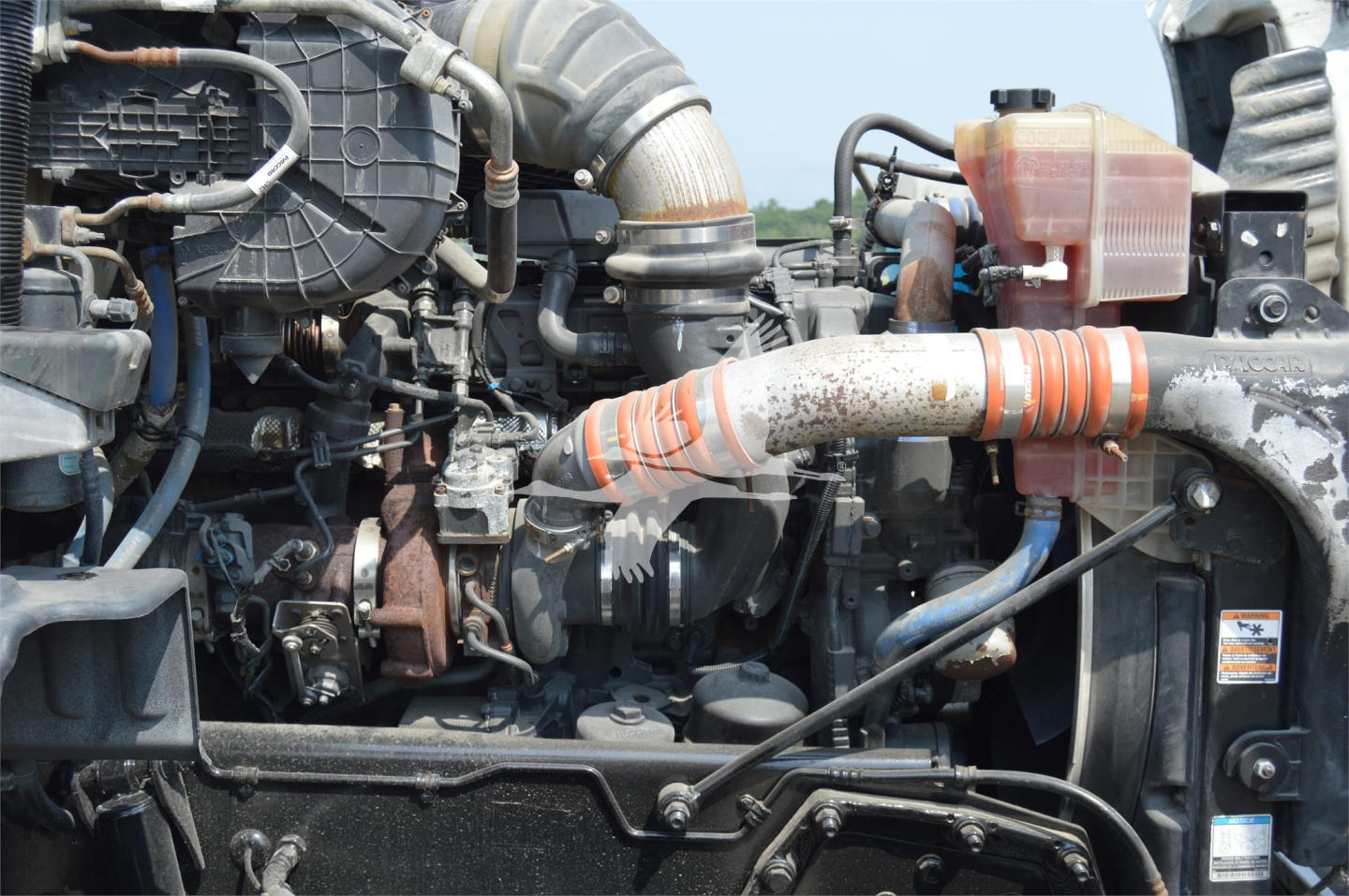 Peterbilt 579 engine bay showing turbocharger, intercooler piping, radiator and coolant reservoir with hoses.