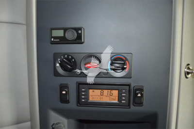 Peterbilt 579 cab interior controls panel with climate dials, radio, and digital clock displaying 8:16.