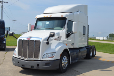 Peterbilt 579 conventional sleeper truck in white, front left view with grille and aerodynamic cab, showing large chrome bumper and dual rear axles.