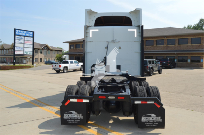 Peterbilt 579 tractor cab rear showing dual rear wheels and chassis with mud flaps and frame, concrete lot in background.