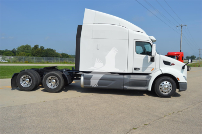 Peterbilt 579 tractor-trailer side profile showing sleeper cab and dual rear axles in a parking lot.