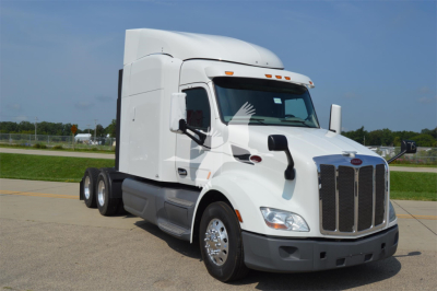 Peterbilt 579 truck in white, side view showing cab with sleeping area and dual rear axles, chrome grille, and large side mirrors.