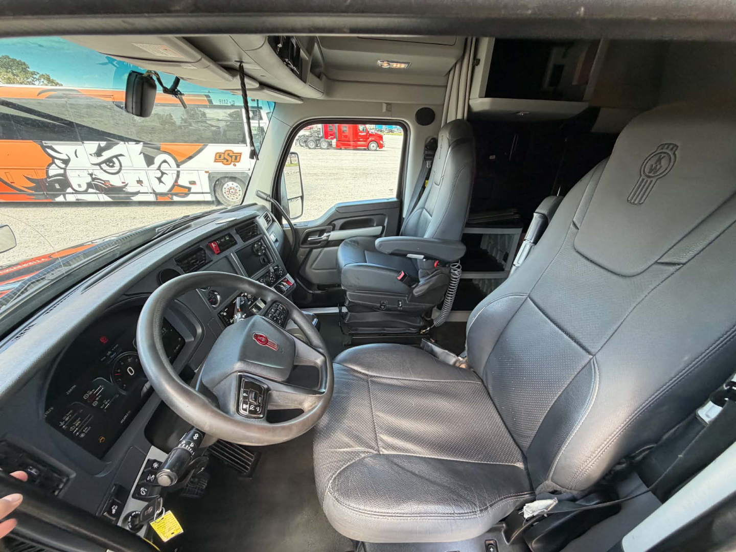 Kenworth T680 truck interior cabin view showing steering wheel, driver seat, and dashboard with controls.