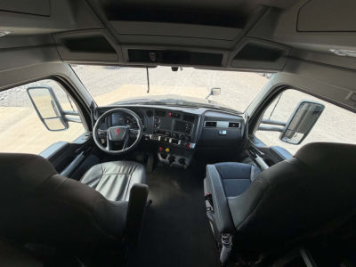 Kenworth T680 truck cab interior showing steering wheel, dashboard with gauges, center control panel, and driver and passenger seats.