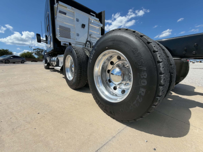 Kenworth T680 chassis and dual rear wheels showing wheel rims and tire sidewalls; cabin area visible with metal exterior and exhaust/air intake panels.