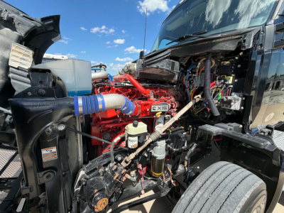 Kenworth T680 engine bay showing red engine components and black cab interior visible, with hoses and wiring