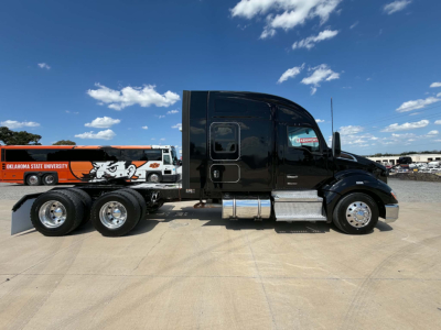 Kenworth T680 conventional sleeper tractor in black, side view showing chrome fuel tanks and dual rear axles with a SAG trailer unit attached.