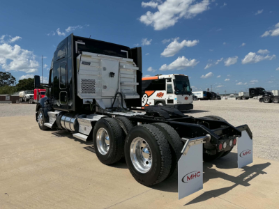Kenworth T680 tractor with fifth wheel removed showing rear and fuel tanks; white engine bay components and windowed sleeper cab; dual rear axles and mud flaps.