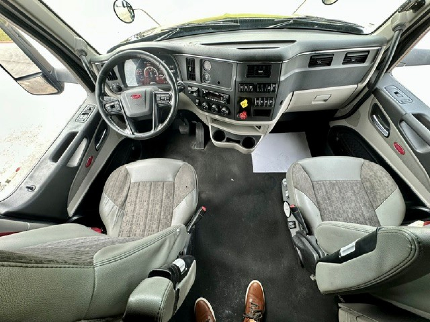 Peterbilt 579 cab interior showing steering wheel, dashboard gauges, center console, and front seats.