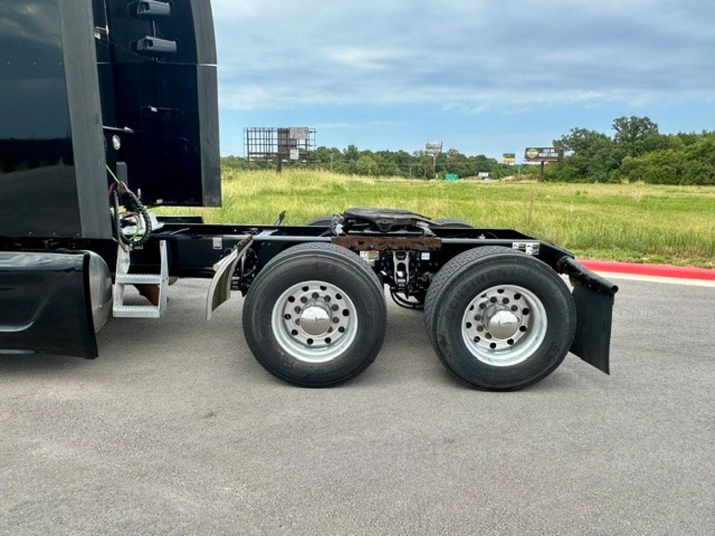 Peterbilt 579 rear undercarriage view showing dual rear axles with wheels and suspension, part of truck chassis, with some wiring and frame components visible.