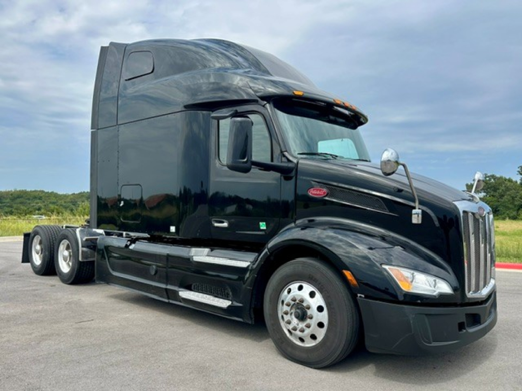 Peterbilt 579 on lot showing sleeper cab, black paint, side profile with dual rear axles and chrome accents.
