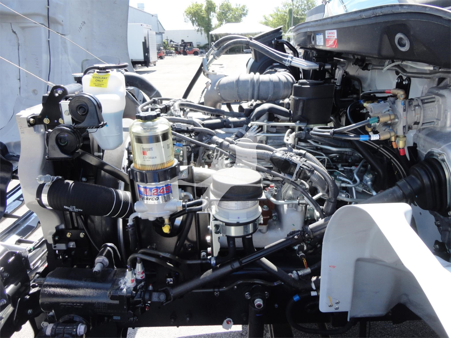 Engine bay of a 2022 Hino 268A rollback truck showing various components including filters, hoses, and metal machinery.
