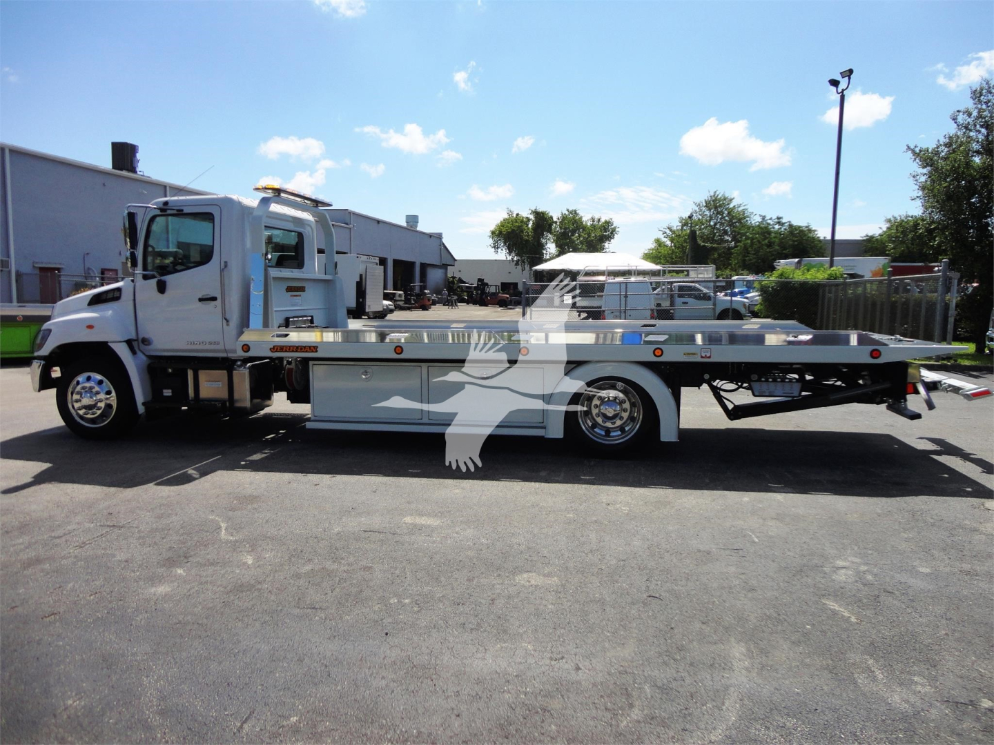 2022 Hino 268A rollback tow truck side view showing flatbed and cab with stock number J51795 in a lot.