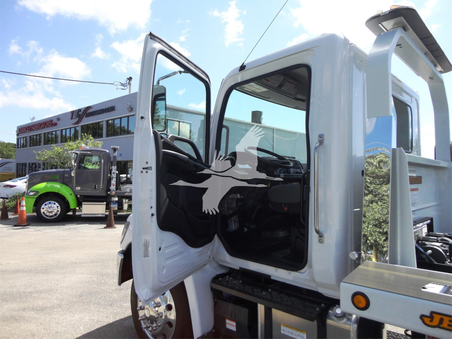 Truck cab interior visible with open door, 2022 Hino 268A rollback truck in background.
