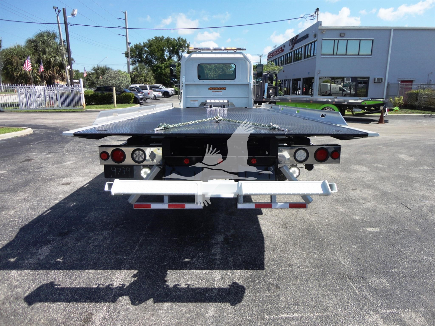 Rear view of a white 2022 Hino 268A rollback tow truck with a flatbed and rear lights.