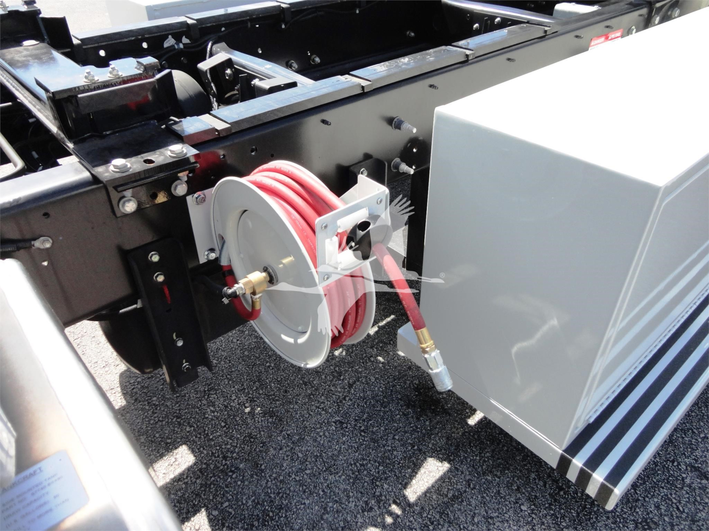 Hino 268A rollback truck chassis with reel hose and storage box, external hose reel mounted on frame near cab; red hose coiled on reel.